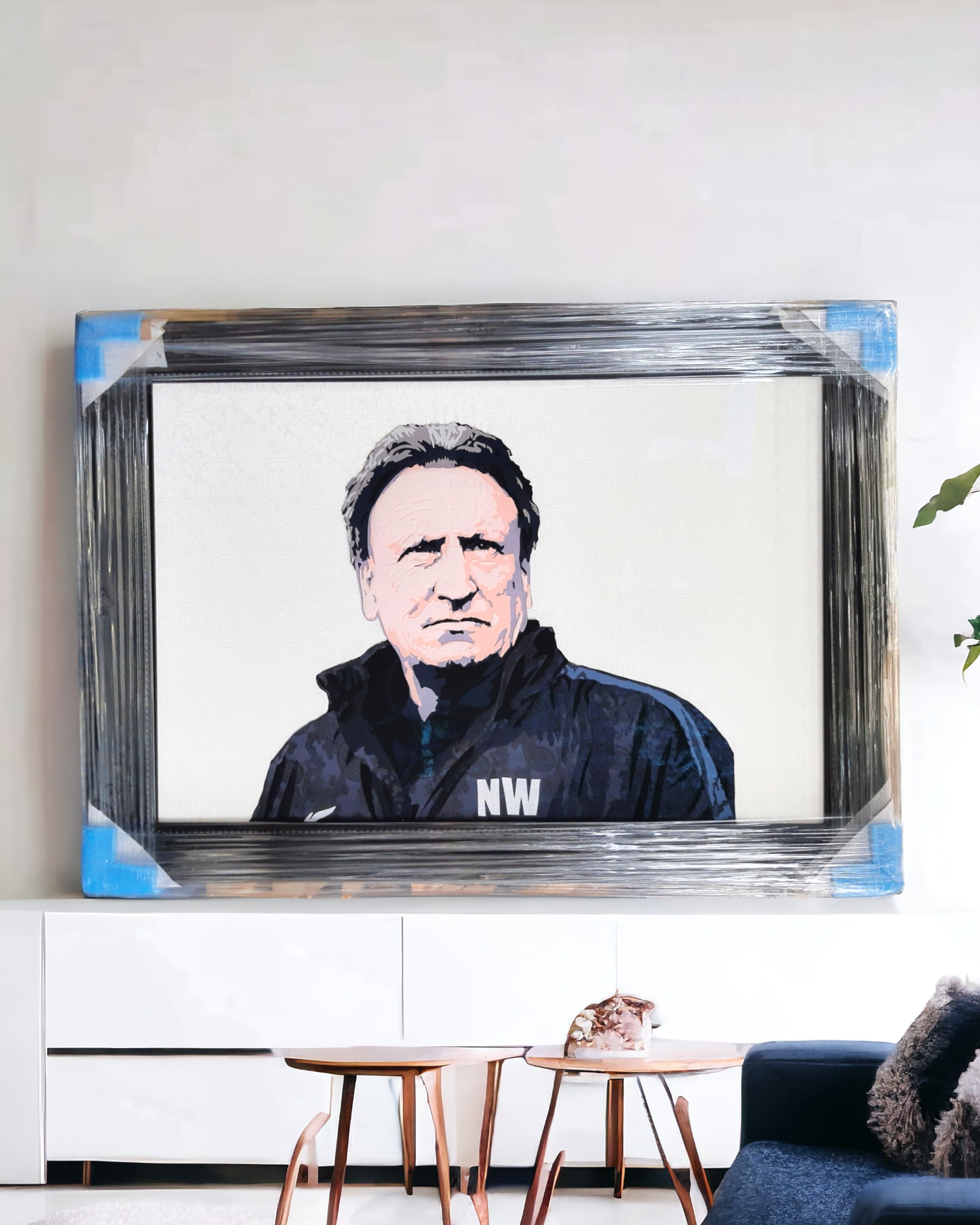 Applique fabric art peice of football manager Neil Warnock in a black Swept framed. White livingroom decor in the background.